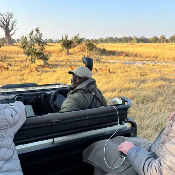 Guests and guide on a game drive across an open plain