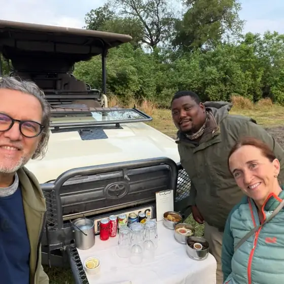 Guests and guide at sundowners beside the vehicle